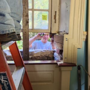 A man measures a window sill with a measuring tape.