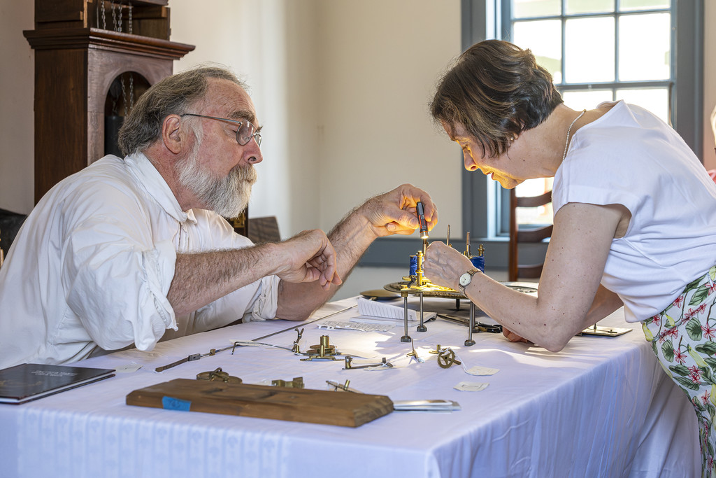 A man and a woman work on putting together a grandfather clock