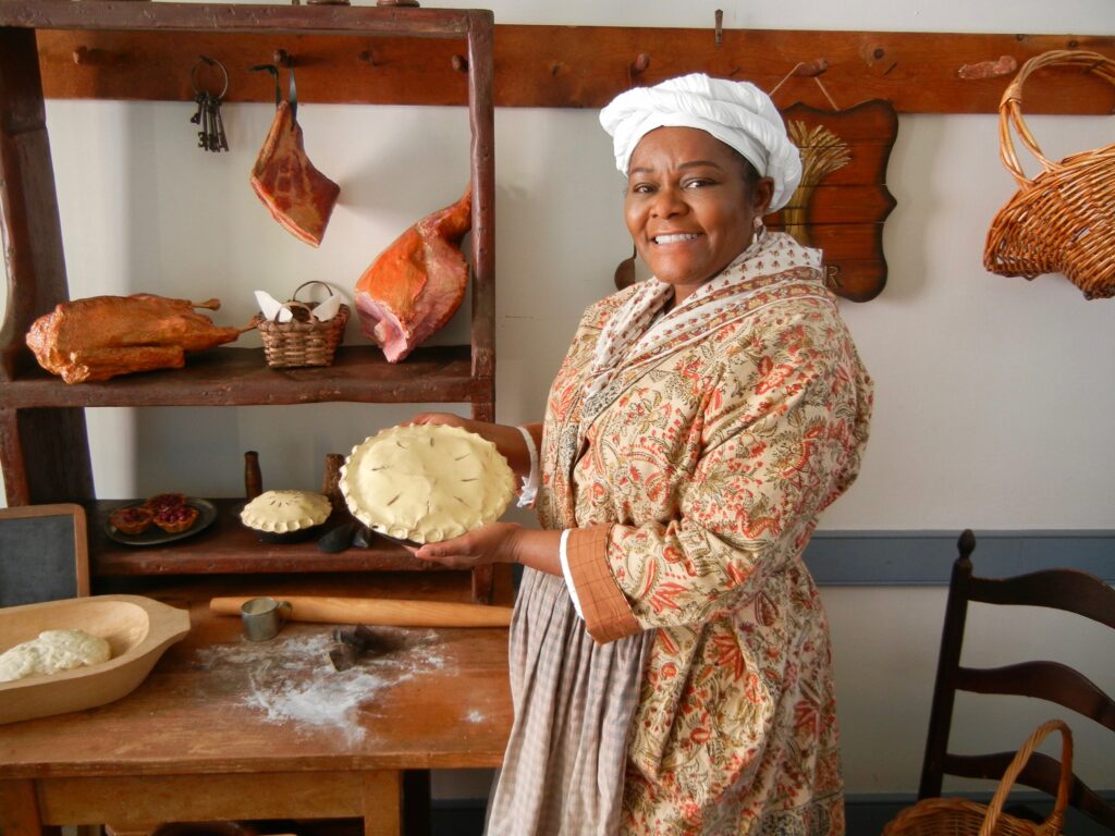 Interpreter dressed in 18th-century attire demonstrates colonial baking inside Hogshead Museum in Annapolis.