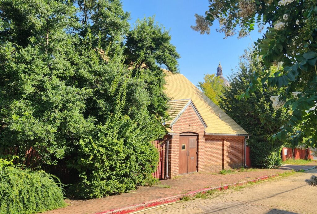 A brick building surrounded by green trees and a blue sky