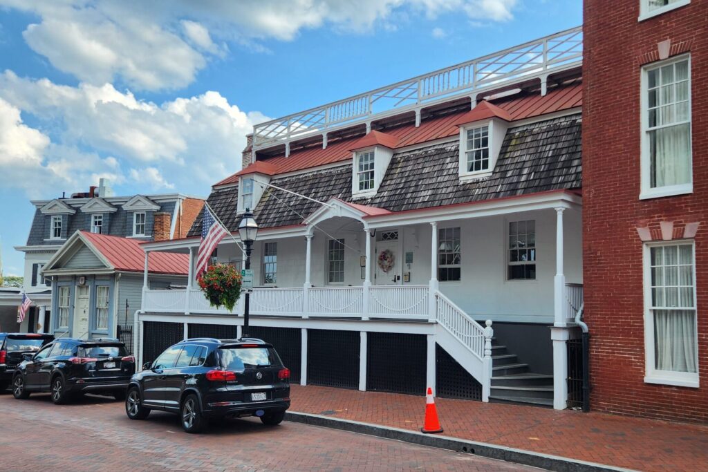 A white wooden building on a brick lined street