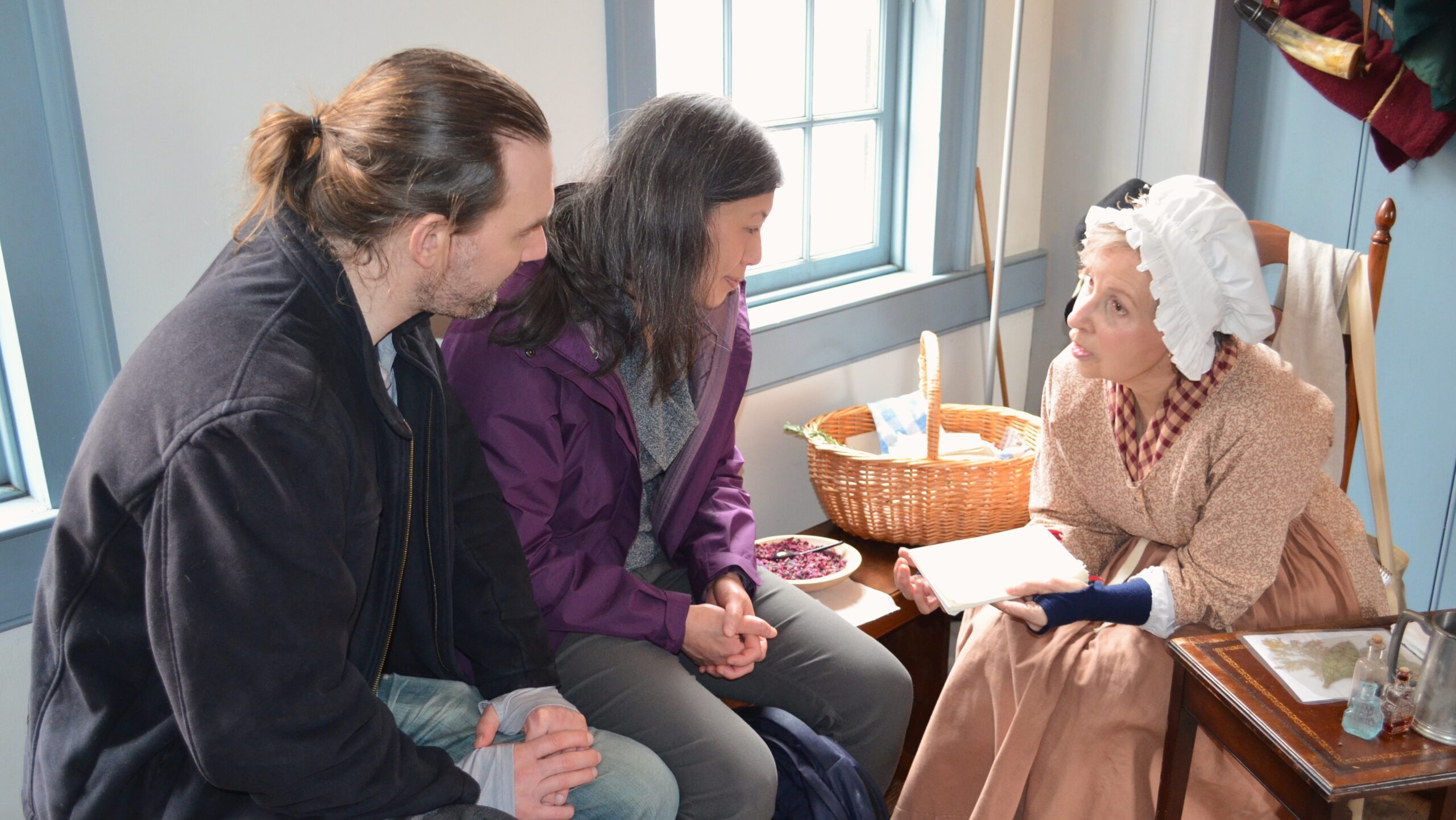 Historic interpreter shares a book with two visitors
