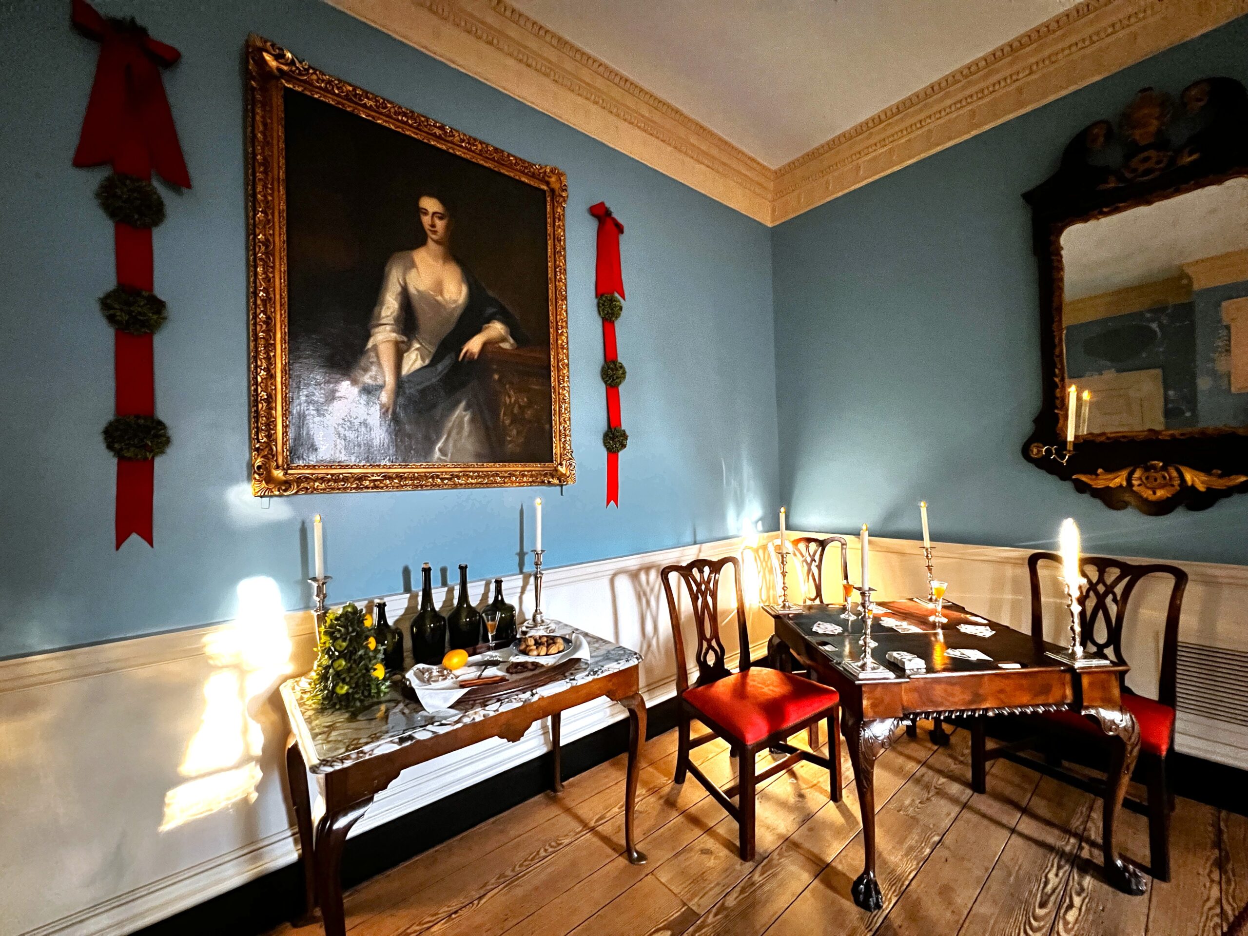 Colonial room with blue walls and a historic card table decorated for the holiday season