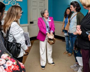 A museum docent shows a group of adults playing cards that would have been used for games in the colonial era.