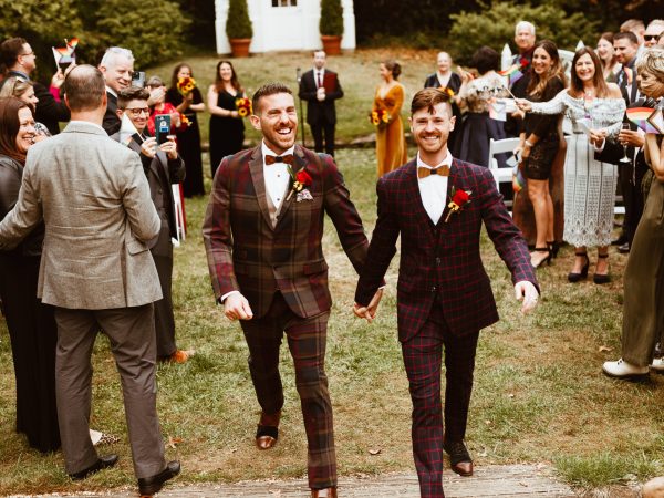 Two grooms walking hand in hand down the garden aisle during their same-sex wedding at the William Paca House, a welcoming Annapolis venue.